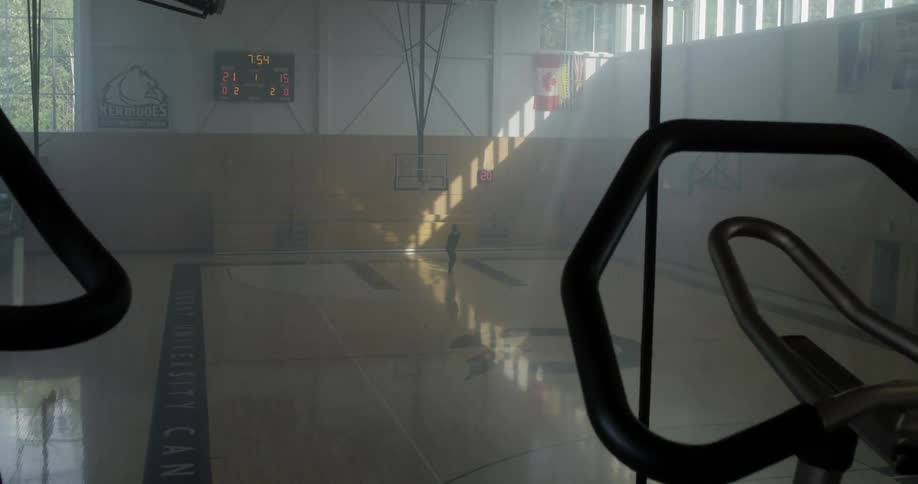 A person practices cheer and dance moves in an empty school gym