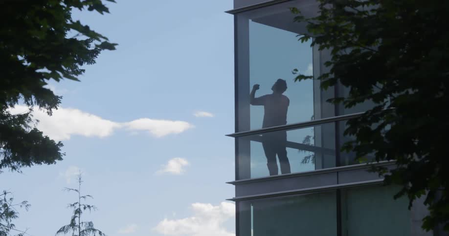 A man inside a building talks on the phone and bangs on a window