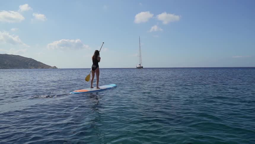 A young woman paddle boards in a lake