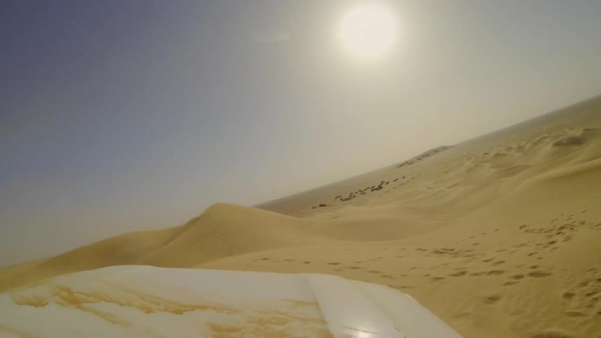 Vehicle travels over the sand in the desert under the bright sun