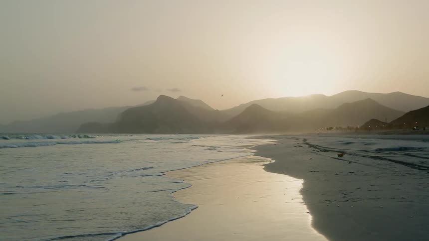 Sun goes down behind the mountains at the beach
