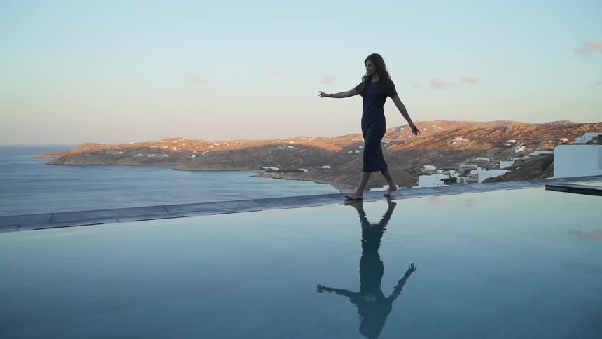 Woman walks on the edge of a rooftop under a blue sky
