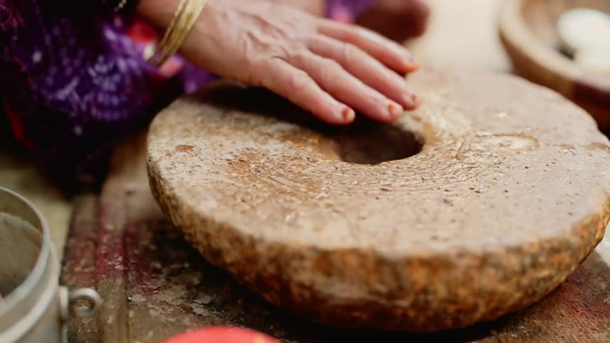 An elderly woman scrubs at the surface of a round object that is wet on its surface