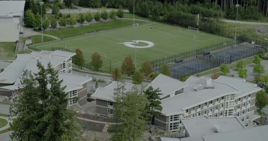A car drives past a football field and school