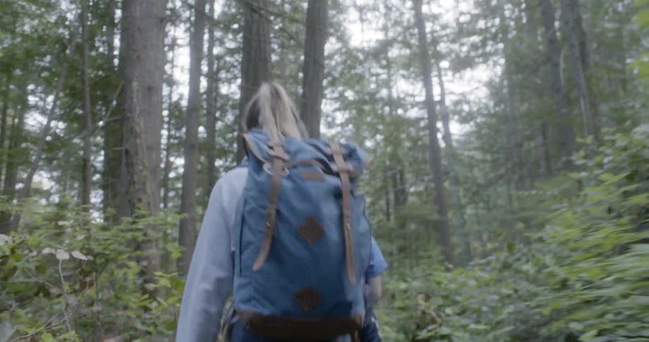 Teenage girls hike up a small slope in the forest