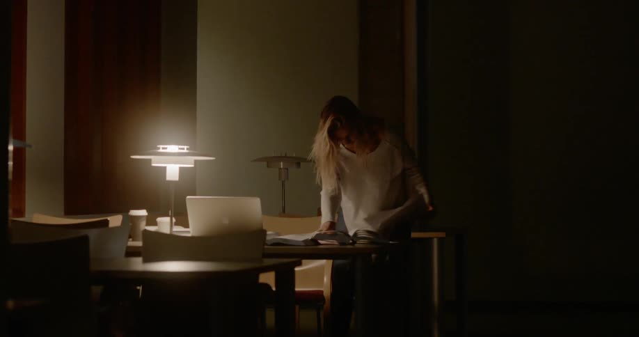 A woman searching through papers on a table in a dimly lit room