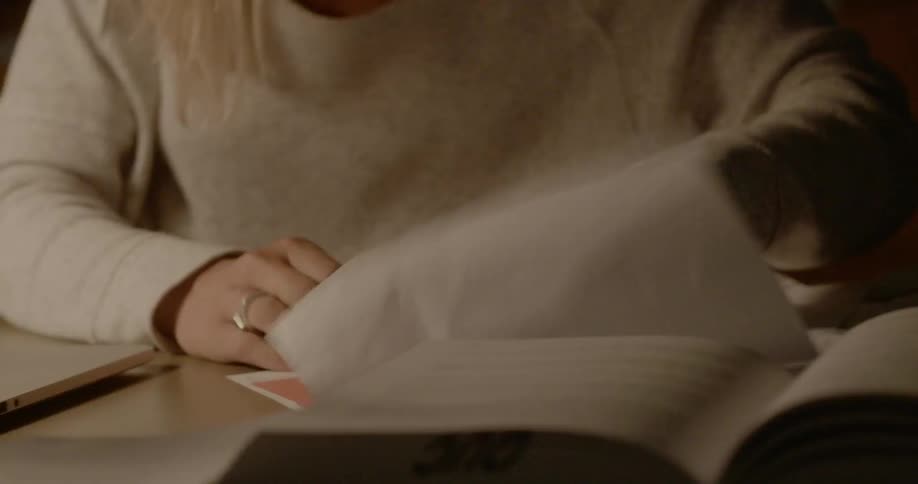 A woman frantically shuffles through papers on a desk