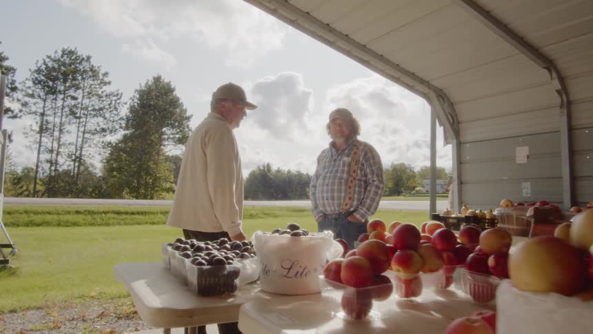 Two older white men converse at a farmers market
