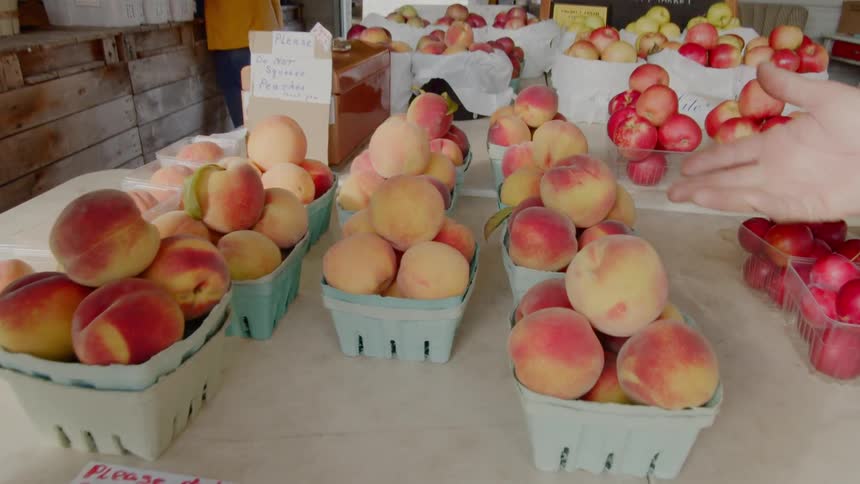 Small baskets of peaches and apples sit on a table