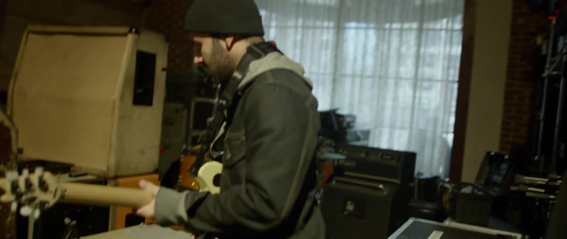 A man puts a guitar around his neck