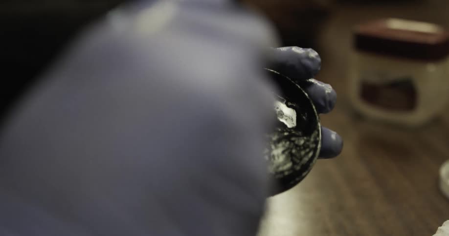 A person rubs a brush in a metal tin of shoe polish