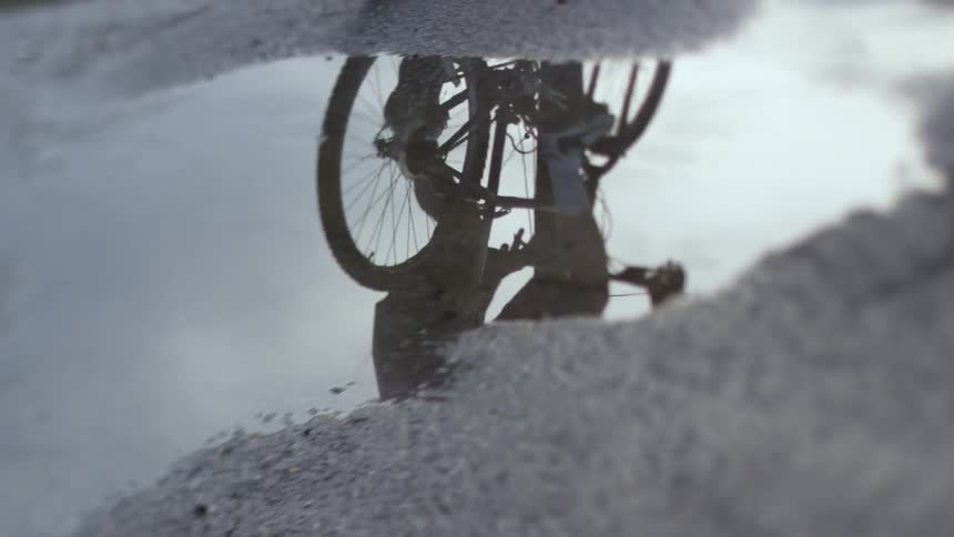 A man bicycles through puddles