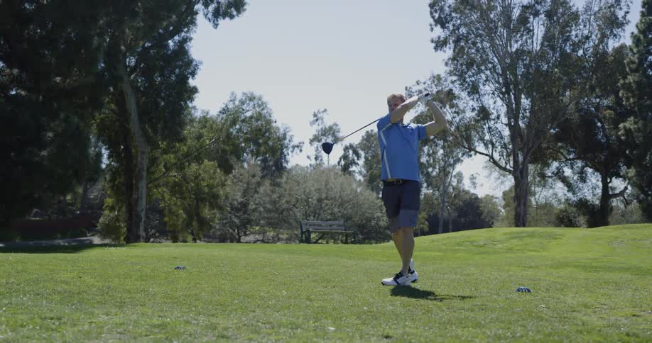 A man uses a golf club and swings to hit a golf ball