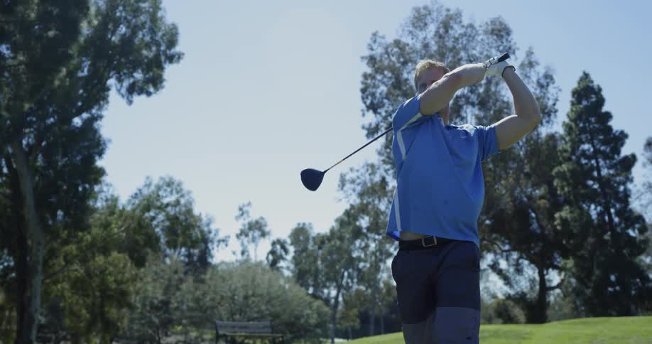 Man tees off and watches golf ball travel