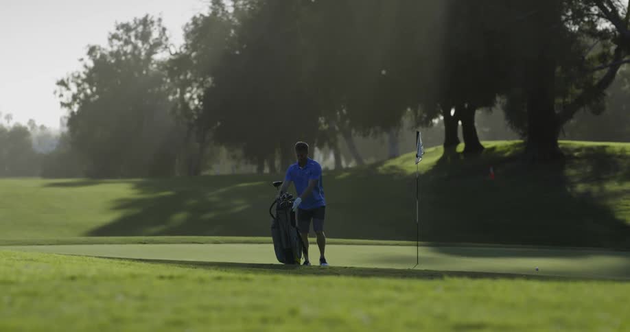 Golf player carrying golf cart bag takes out a club to play the golf on a sunny day