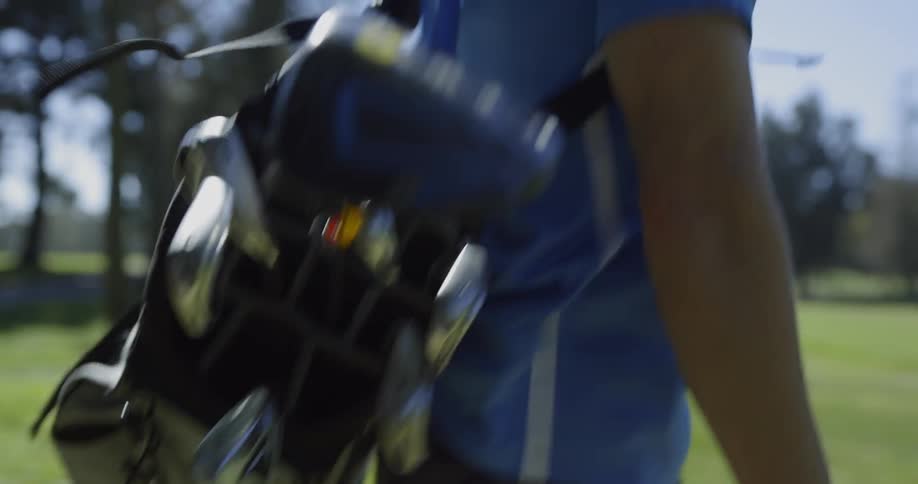 A man walks with a golf bag over his shoulder