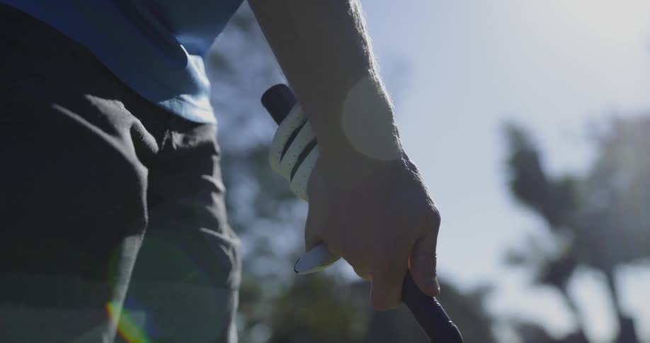Golfer grips golf club with one hand out of glove