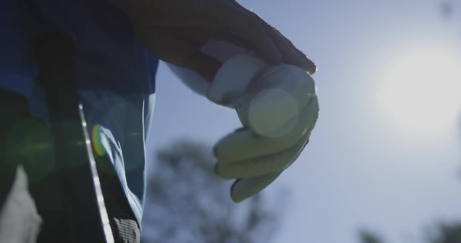 Man puts on golfing gloves before gripping his club