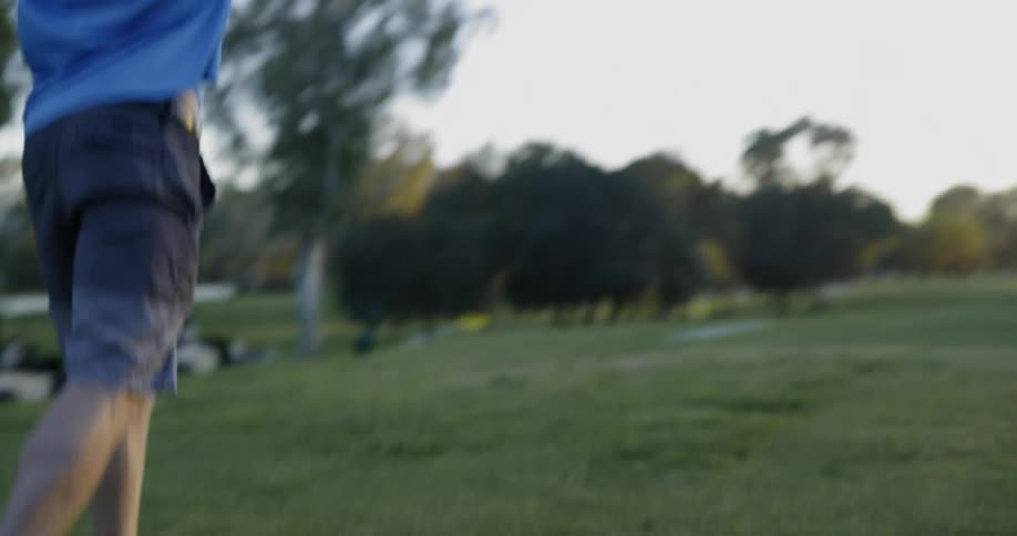 A white male in a blue nike polo shirt hits a golf ball with a driver on a golf course