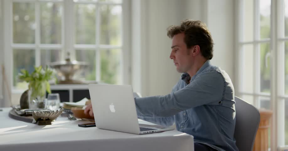Man working on his laptop sitting at a table indoors