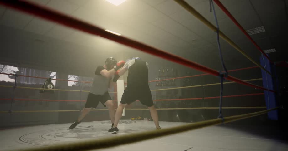 Two boxers train and hit each other in the ring
