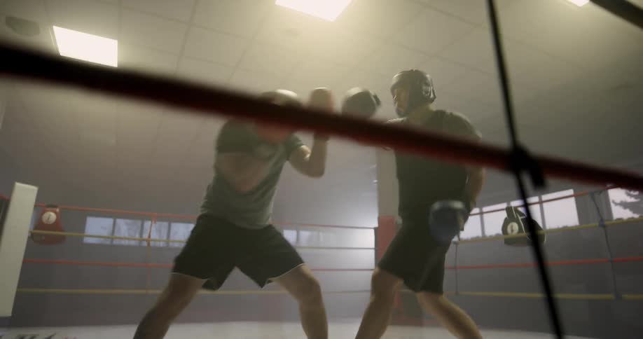Two men punch and hit each other as they spar in a boxing ring