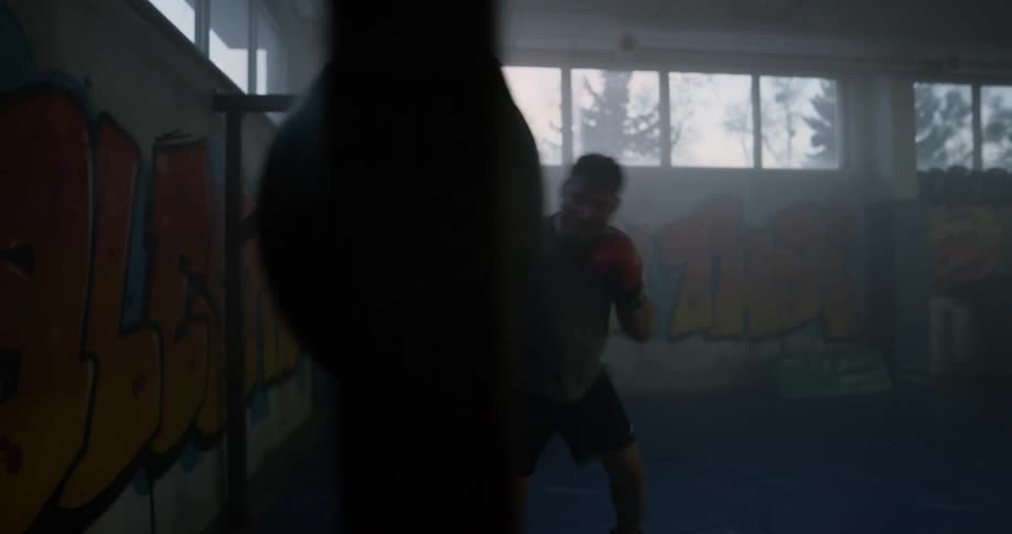 A manis punching a heavy bag around in the gym