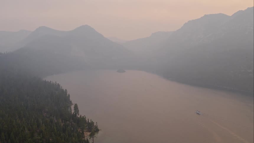 A lake set between forested mountains as low sun creates a red sky