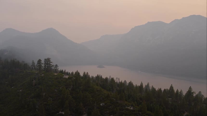 Fog covers river and mountain bordered by forest