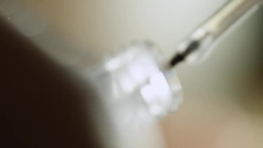 A small brush circles the opening of a small glass bottle