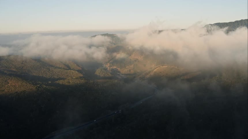 Low lying clouds hang over road bordered by mountains