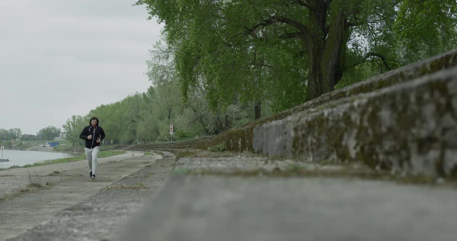 A man jogs along a pathway beside a waterway