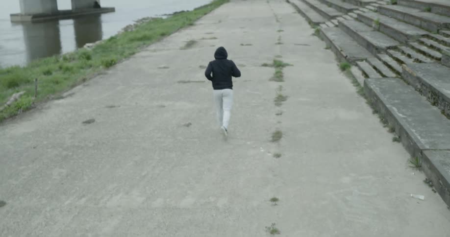 Man runs along the road next to the river on a cloudy day