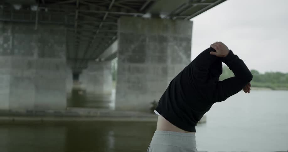 A person runs and then stretches in front of the water