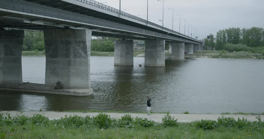 A man is jogging under the bridge