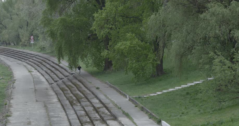 A jogger runs up path steps and continues jogging in the park