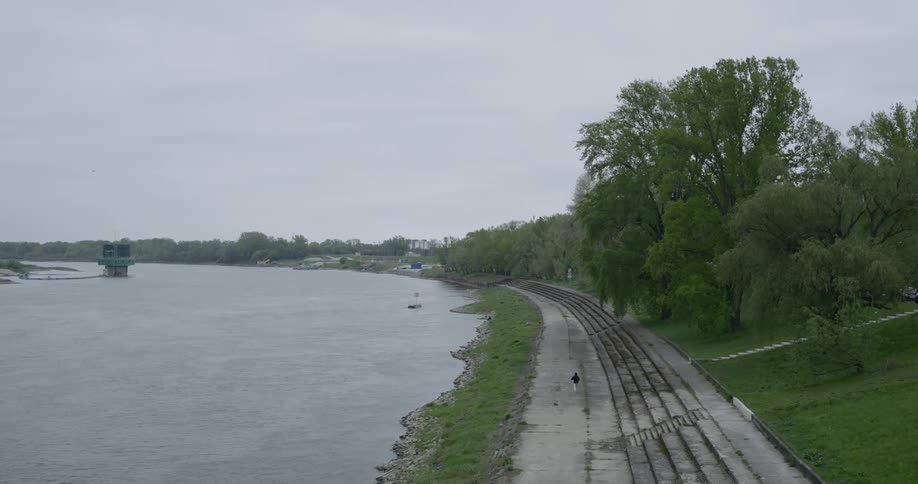 A person jogging along a river bank on a cloudy day