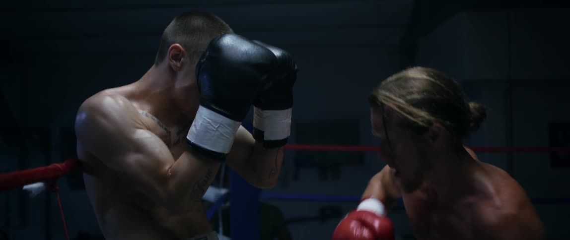 A man in red punching another man in a boxing ring