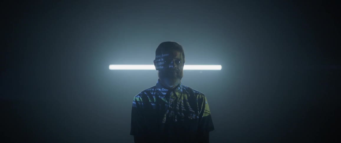 Man standing in dark room while light projects on him