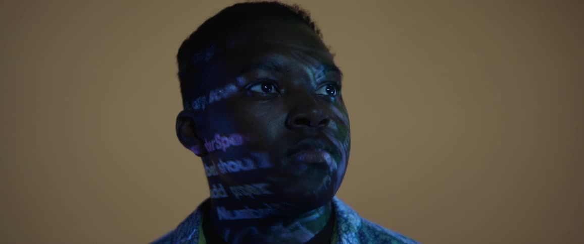 Close up of black man with word projection lighting on his face