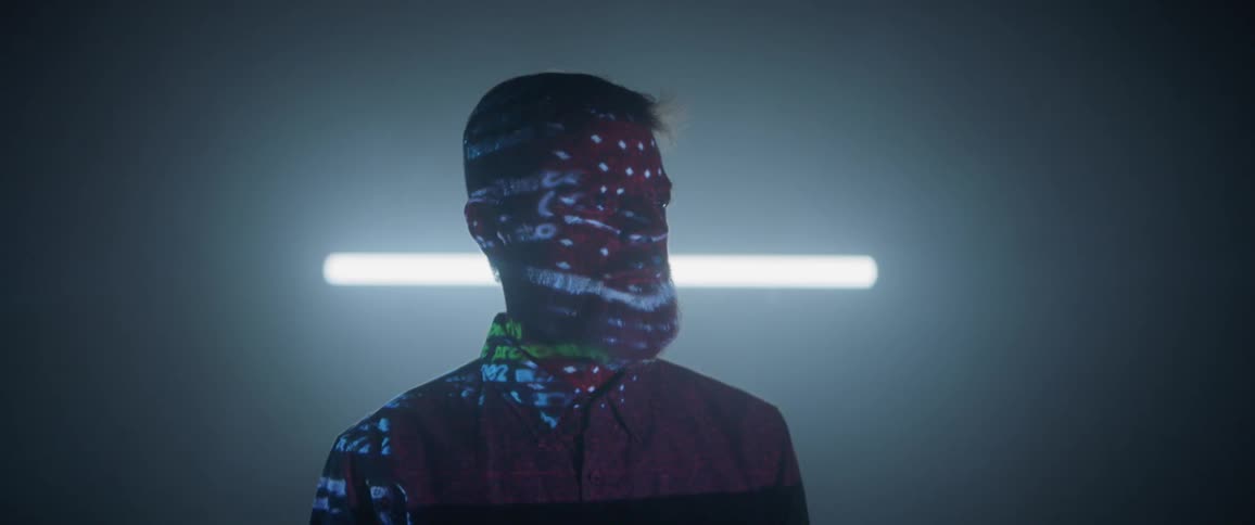The projector is flashing on a mans face in the dark