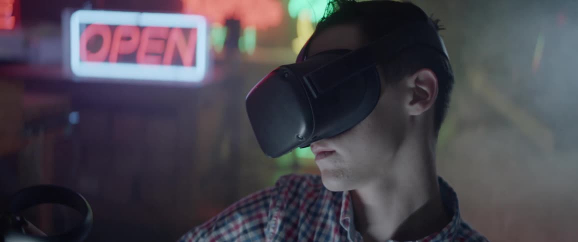 A man sits in a dimly lit and hazy room while wearing a virtual reality headset