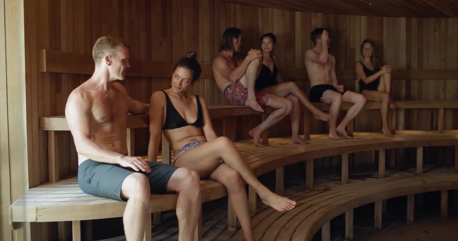 Three white males and three white females are talking and relaxing in a sauna