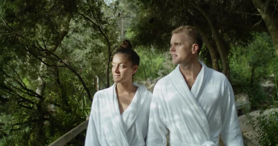 Couple wearing robes walking through a woodsy path