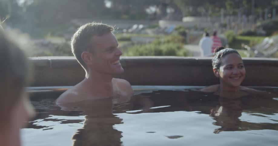 People relaxing in a kind of thermal bath surrounded by bushes
