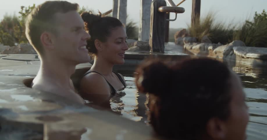 People relaxing in a kind of thermal bath surrounded by bushes