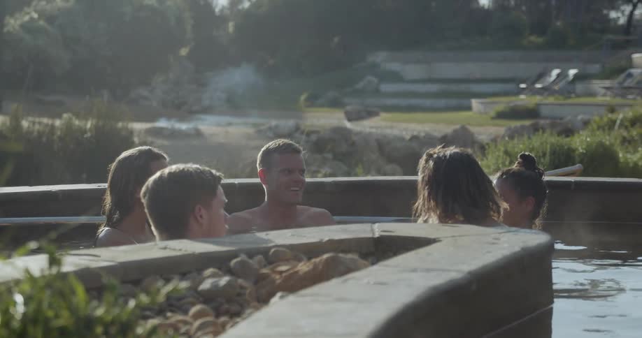 A group of people sit in an outdoor hot tub