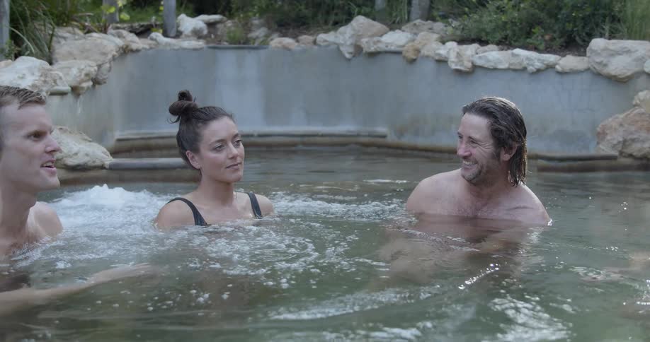 People relaxing in a kind of thermal bath surrounded by bushes