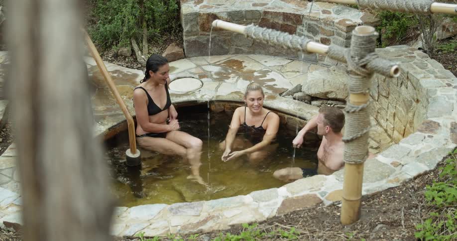 People relaxing in a bath spa pool surrounded by trees