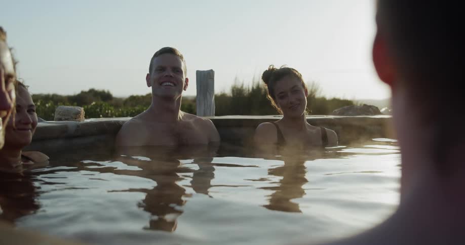 Several couples sit in a hot tub and talk